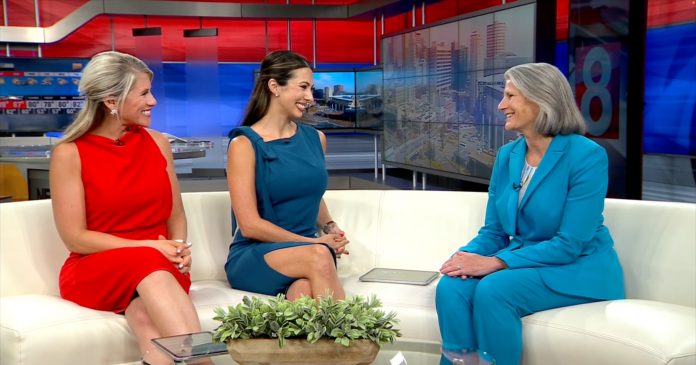 Three women sit on a television studio couch during a WTNH CT Live interview. Dr. Sandra Bulmer, wearing a blue suit, discusses Southern Connecticut State University’s upcoming women’s sports celebration.